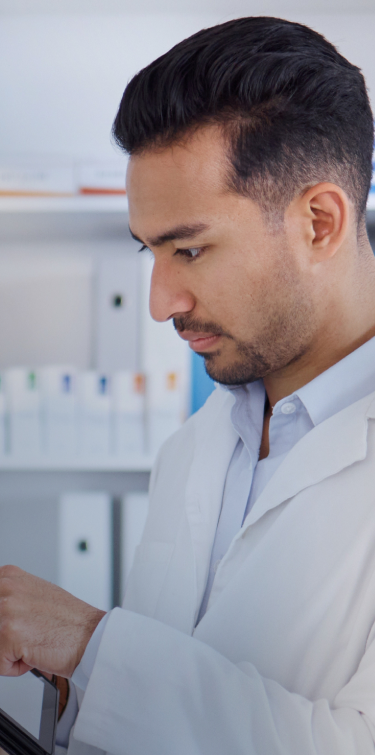 Man in white lab coat touch and ipad an reviewing inventory solutions